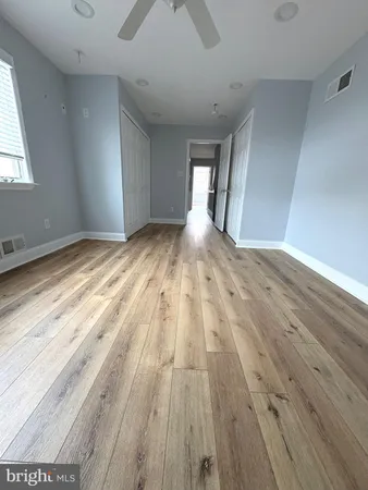 a view of empty room with wooden floor and fan