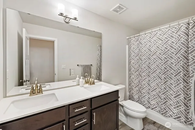 a bathroom with a double vanity sink toilet and a mirror