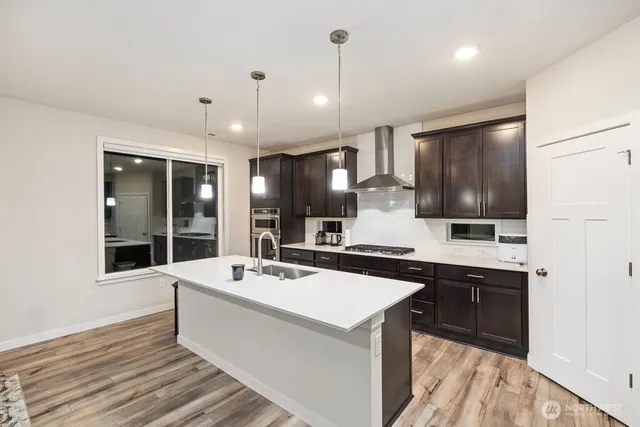 a large white kitchen with a sink and dishwasher a stove top oven with wooden floor