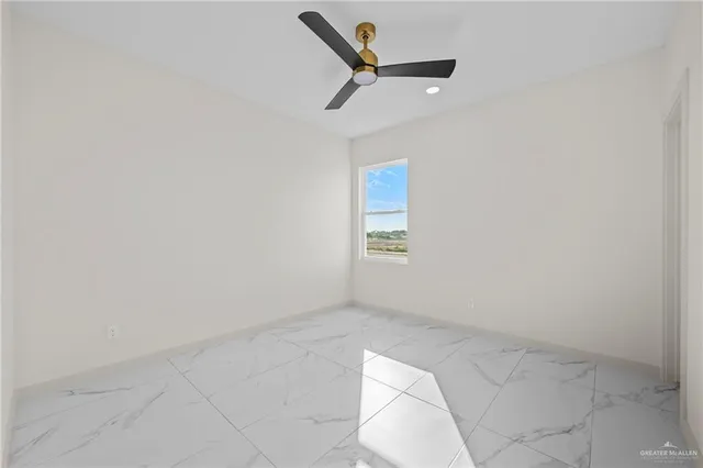 an empty room with a ceiling fan and wooden floor