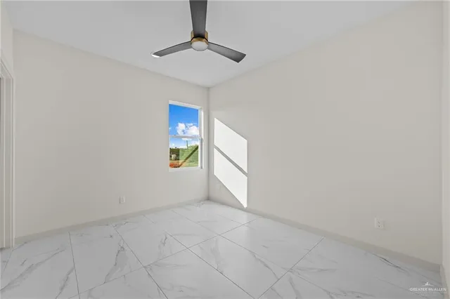 a view of an empty room and chandelier fan