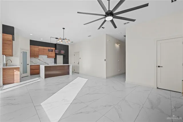 a view of a livingroom with a ceiling fan and kitchen space with a stove