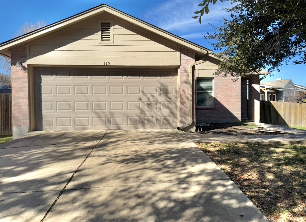 View of front of property with brick siding, driveway, and a garage