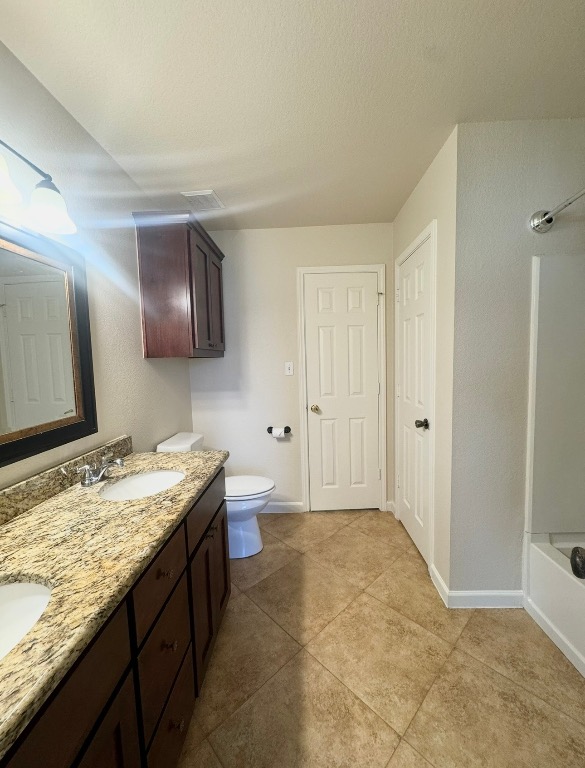 110 Comal Cove Elgin, TX 78621 - Photo 14 of 25 Full bath with double vanity, bathing tub / shower combination, light tile patterned floors, and a textured ceiling