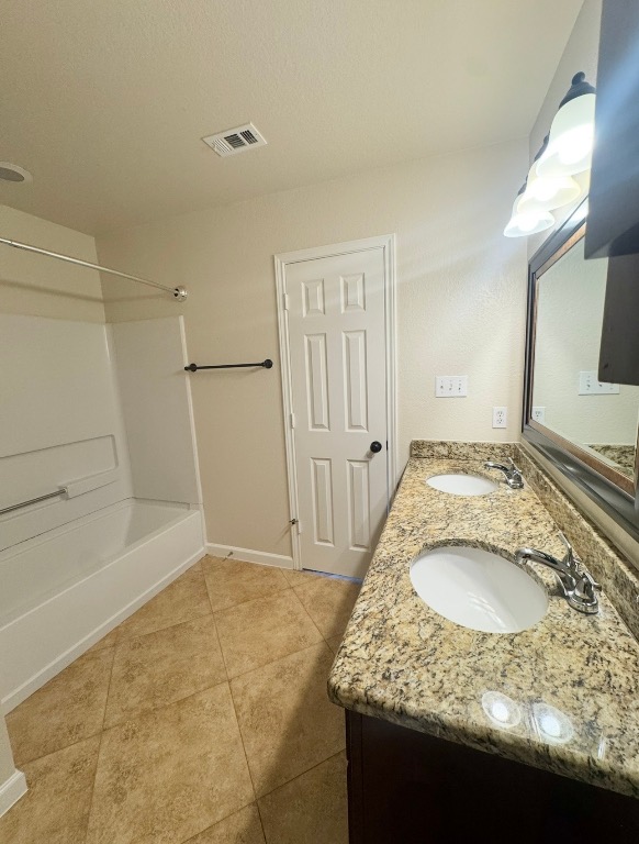110 Comal Cove Elgin, TX 78621 - Photo 15 of 25 Bathroom featuring tub / shower combination, double vanity, and light tile patterned flooring