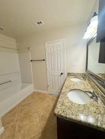 a bathroom with a granite countertop sink a mirror and a bathtub