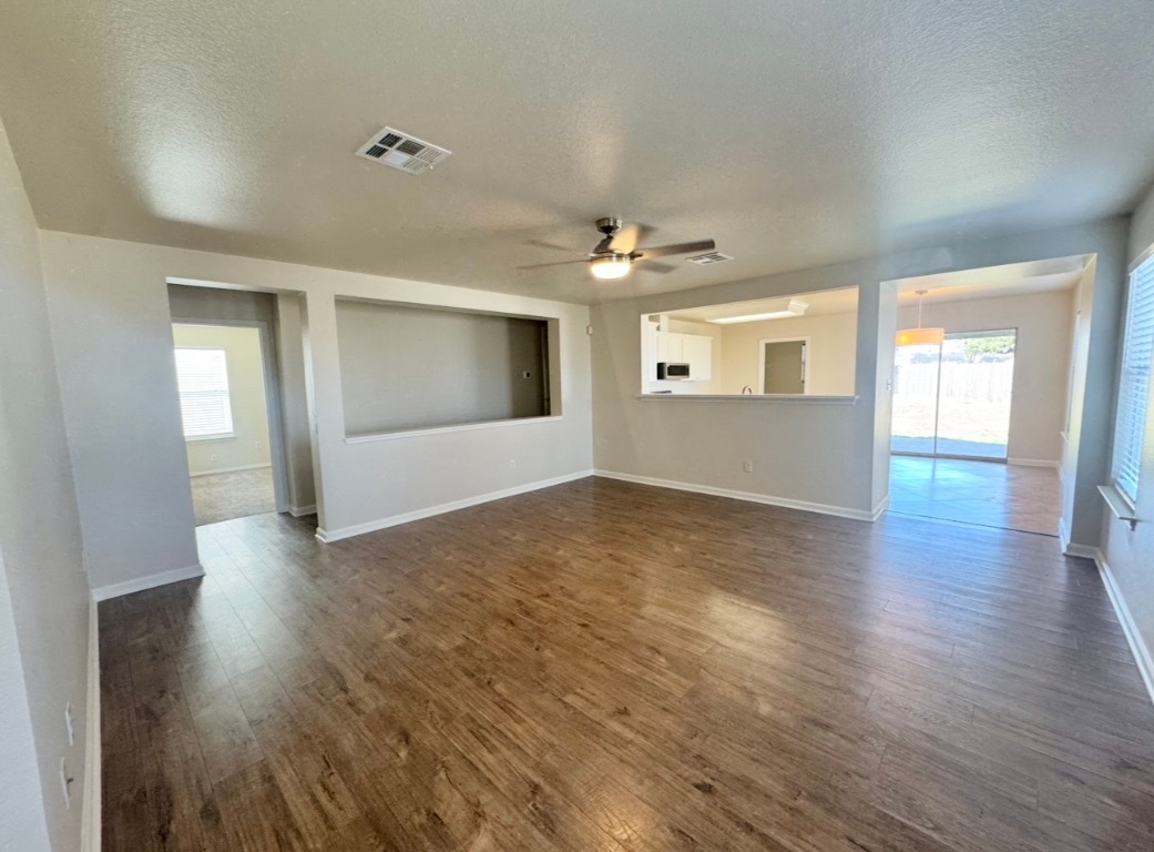 110 Comal Cove Elgin, TX 78621 - Photo 4 of 25 Unfurnished living room, a ceiling fan, natural light, and dark wood floors
