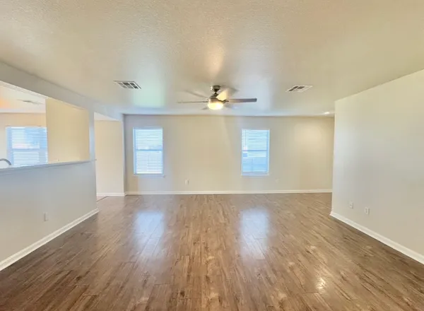 an empty room with wooden floor and windows