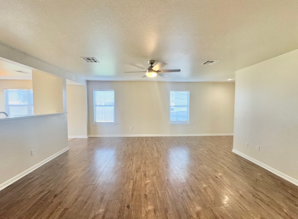110 Comal Cove Elgin, TX 78621 - Photo 6 of 25 Empty room with a textured ceiling, dark wood-style flooring, and a ceiling fan