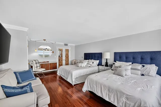 a bedroom with two beds and a large mirror with wooden floor