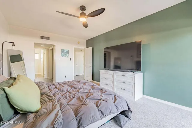 a bedroom with a large bed and a flat tv screen on dresser