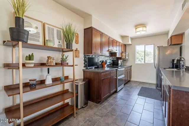 a kitchen with kitchen island granite countertop a refrigerator oven a sink dishwasher and cabinets with wooden floor