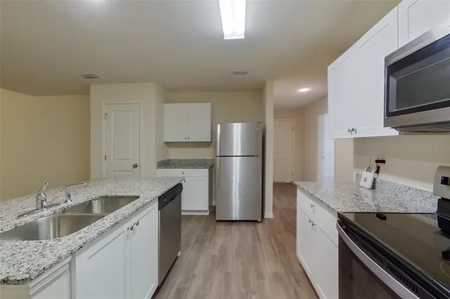 a kitchen with a sink dishwasher a refrigerator and a stove top oven with wooden floor