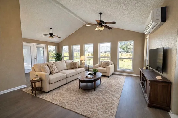 a living room with furniture a ceiling fan and a flat screen tv
