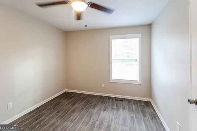 an empty room with wooden floor chandelier fan and window