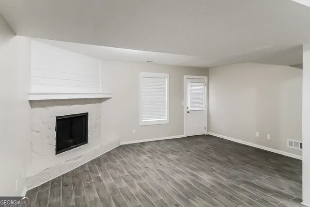 a view of empty room with wooden floor and fireplace