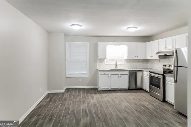 a kitchen with a sink wooden floor and stainless steel appliances