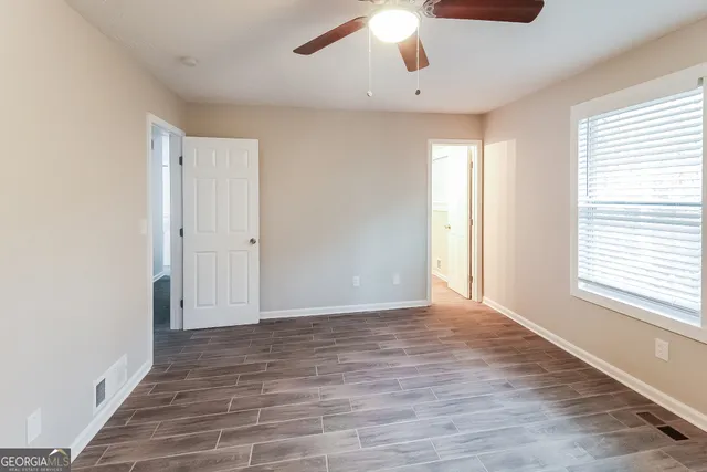 a view of an empty room with wooden floor and a window