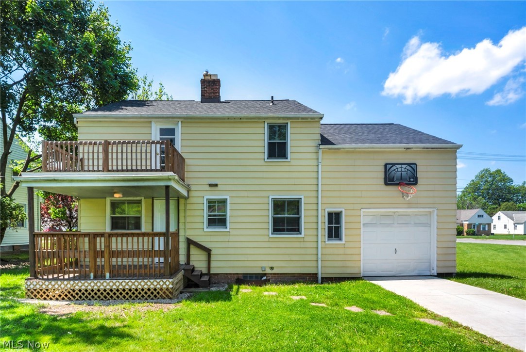 2313 North Taylor Road Cleveland Heights, OH 44112 - Photo 28 of 32 Rear exterior featuring a two-story wooden deck, attached garage with a white overhead door, yellow siding, and a clear concrete driveway