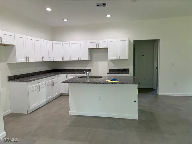 a kitchen with stainless steel appliances granite countertop a stove a sink and white cabinets
