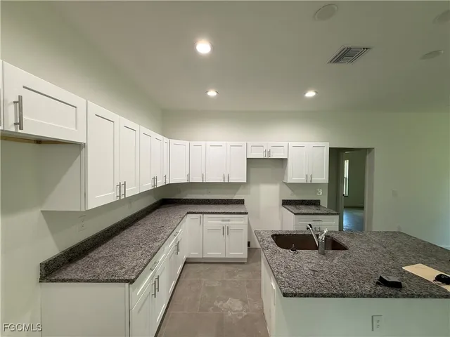 a kitchen with granite countertop a sink a stove and cabinets