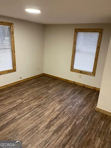 a view of an empty room with wooden floor and a window