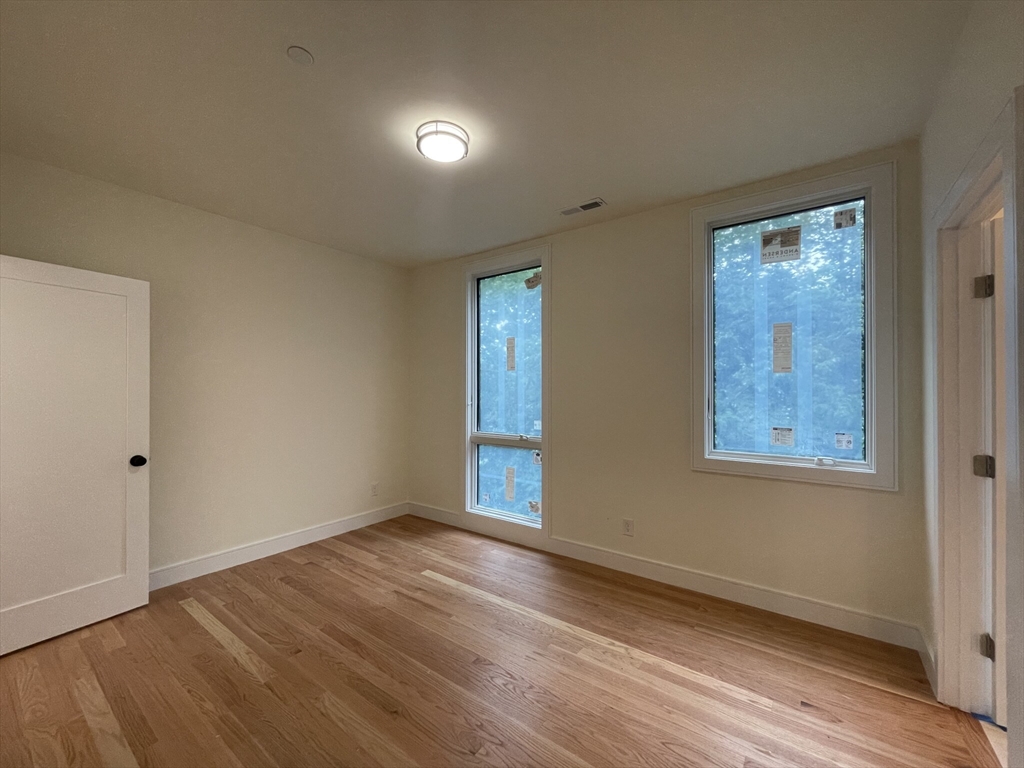 65 Cameron Street, Unit 4 Brookline, MA 02445 - Photo 4 of 13 a view of an empty room with wooden floor and a window