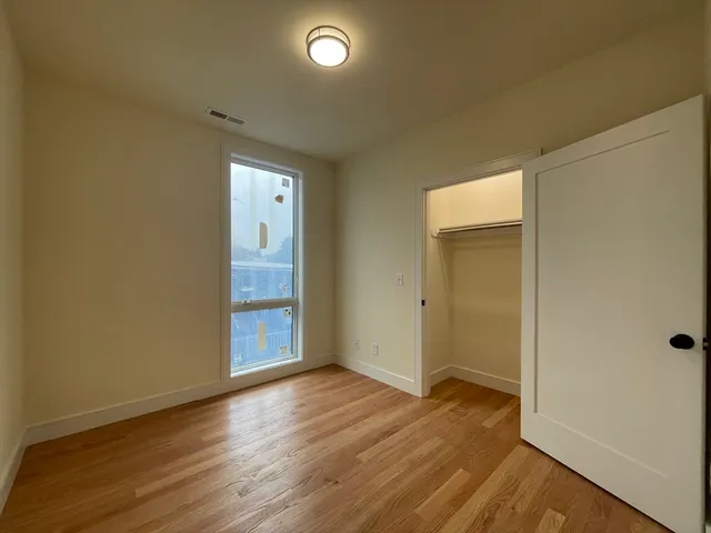 a view of an empty room with wooden floor and closet