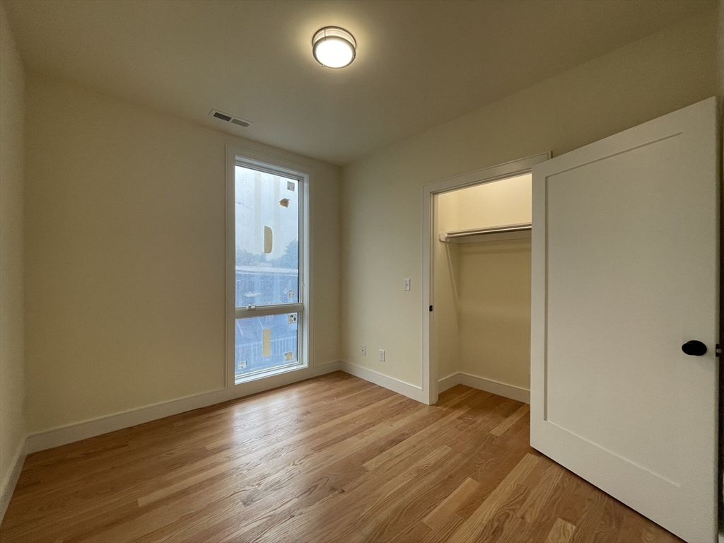 65 Cameron Street, Unit 4 Brookline, MA 02445 - Photo 8 of 13 a view of an empty room with wooden floor and closet