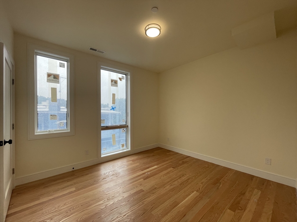 65 Cameron Street, Unit 4 Brookline, MA 02445 - Photo 10 of 13 an empty room with wooden floor and windows
