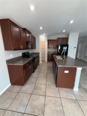 an empty room with wooden floor chandelier and windows