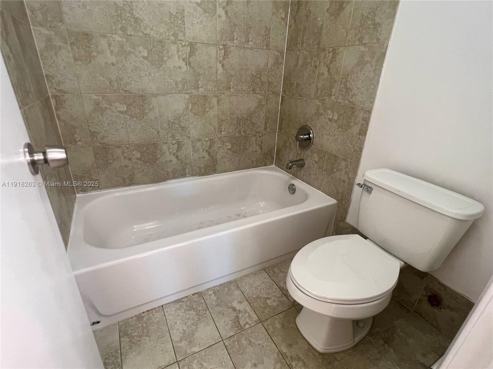 9961 Northwest 9th St Circle, Unit 818 Miami, FL 33172 - Photo 18 of 25 a white toilet sitting next to a bath tub