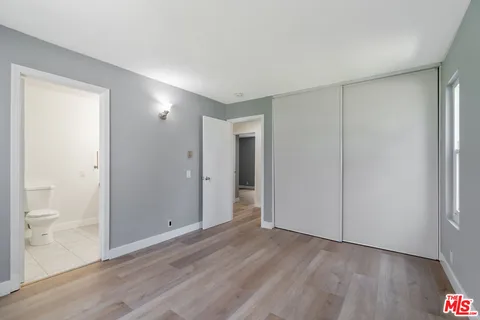 a view of an empty room with wooden floor and a bathroom