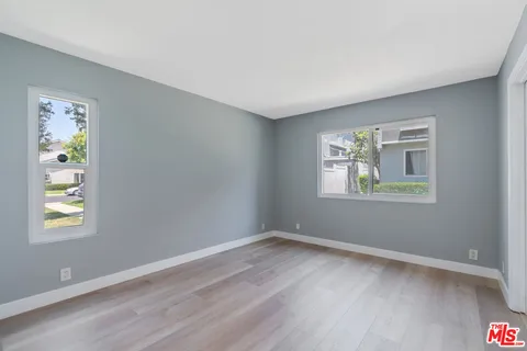 a view of an empty room with window and wooden floor