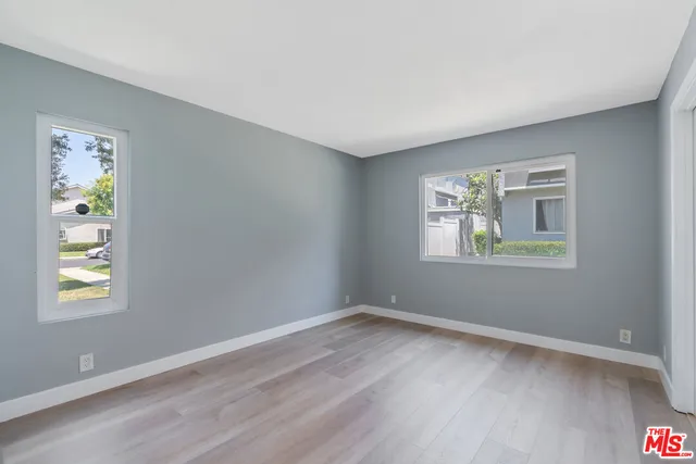 a view of an empty room with window and wooden floor