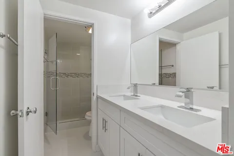a bathroom with a shower sink vanity mirror and toilet