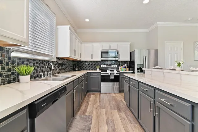 a kitchen with stainless steel appliances a sink dishwasher a stove top oven a refrigerator with wooden floors