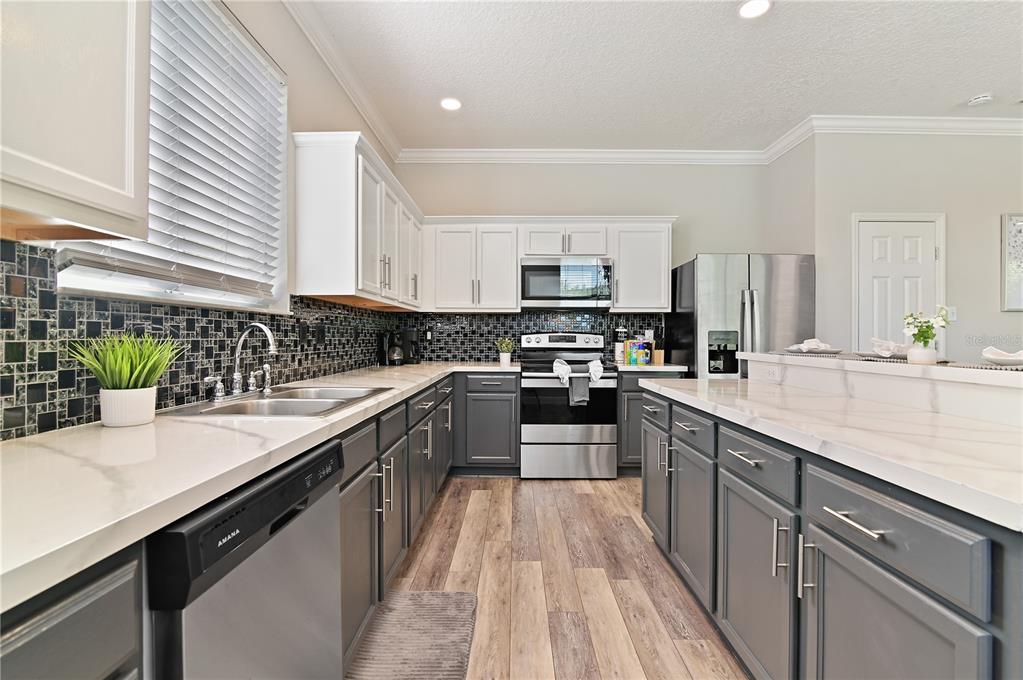 701 Kettering Road Davenport, FL 33897 - Photo 11 of 41 a kitchen with stainless steel appliances a sink dishwasher a stove top oven a refrigerator with wooden floors