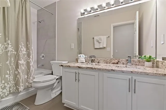 a bathroom with a granite countertop sink toilet and mirror