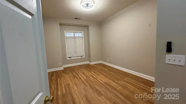 a view of empty room with window and wooden floor
