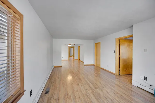a view of empty room with wooden floor and fan