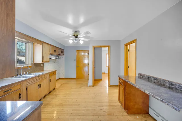 a large kitchen with kitchen island a large window a sink and stainless steel appliances