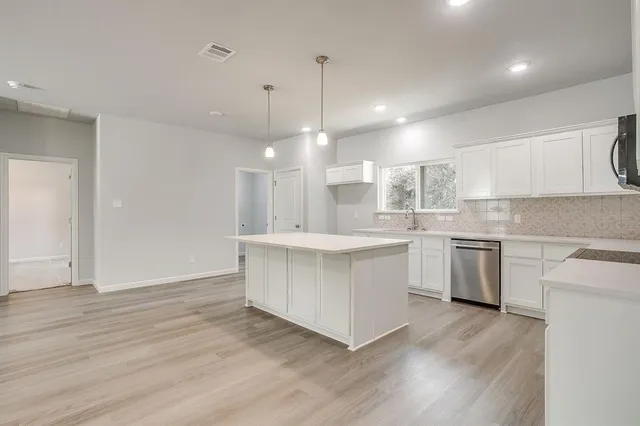 a large kitchen with kitchen island a stove a sink dishwasher and a oven with wooden floor