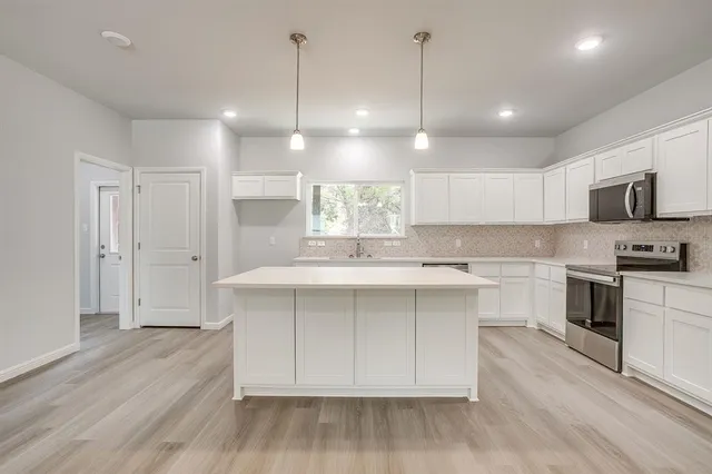 a kitchen with white cabinets and window