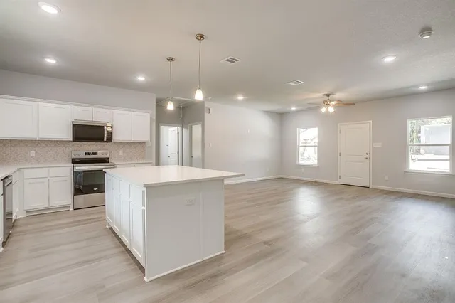 a kitchen with kitchen island a sink appliances cabinets and a large window