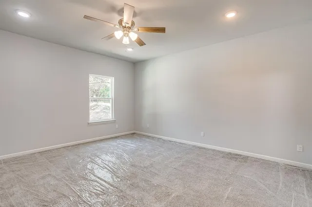 an empty room with windows and chandelier fan