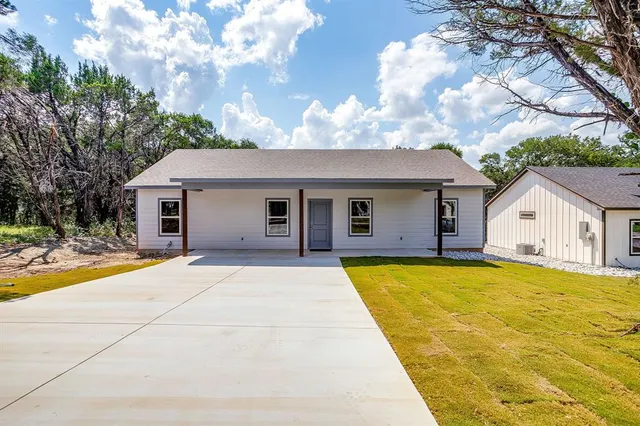 a front view of house with yard and trees in the background