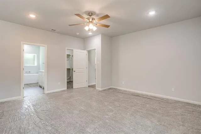 an empty room with a kitchen and a chandelier fan