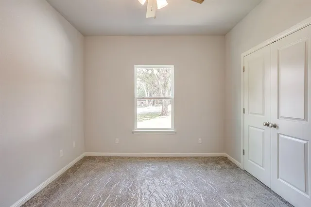 a view of an empty room and chandelier fan