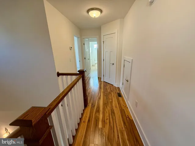 a view of a hallway with wooden floor and stairs